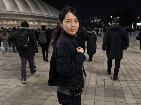 東京 Dome 夜間離場時佳穎背著相機回頭回應主角鏡頭