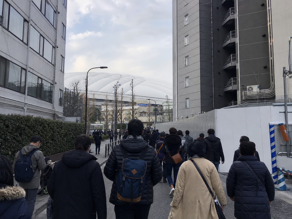 從水道橋步行途中在人潮與建物間看見東京 Dome 白色屋頂