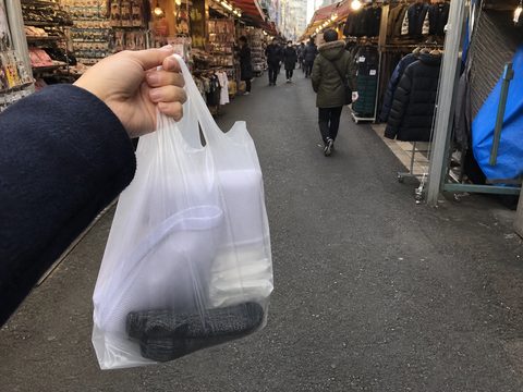 主角在阿美橫丁提著洗衣袋暖暖包與厚襪